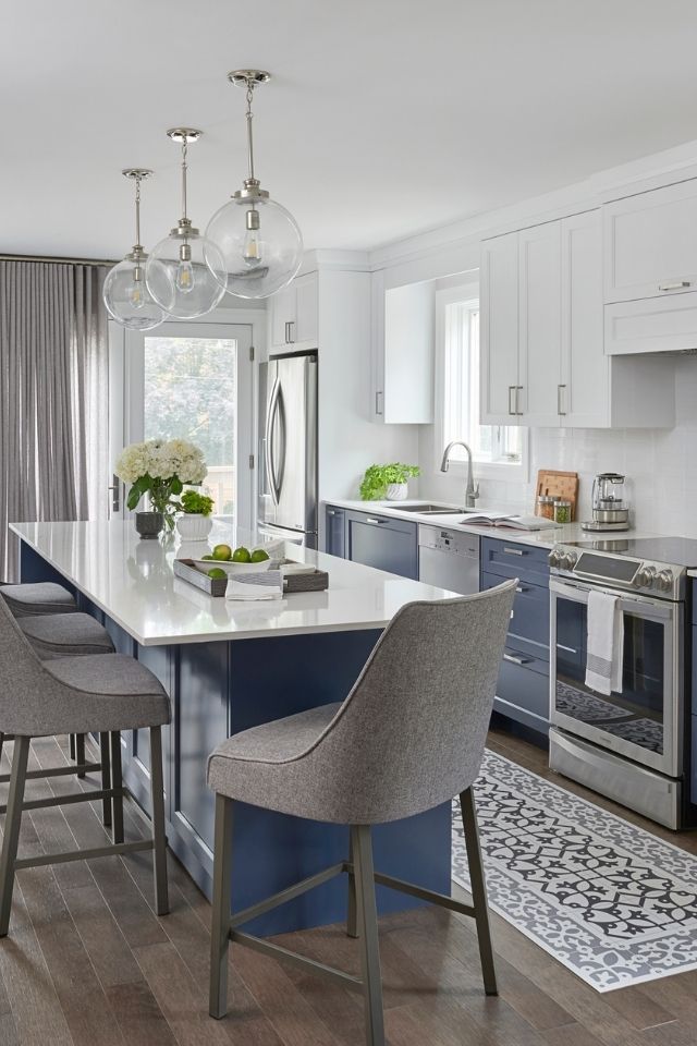 Dark blue lower cabinets with island and rug in white kitchen