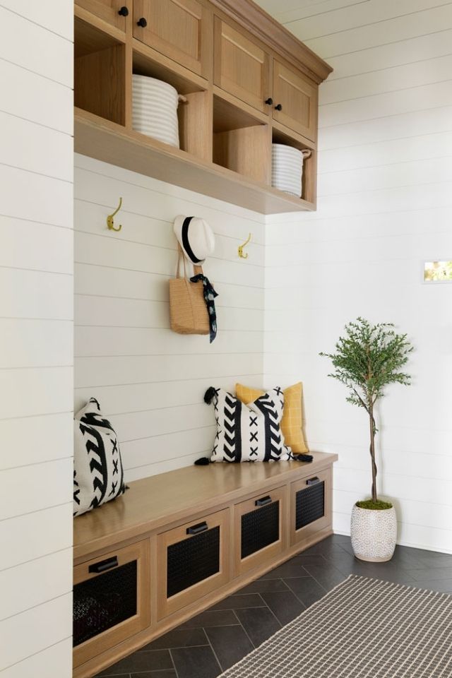 Entryway storage with built-in wood cabinetry and shiplap walls